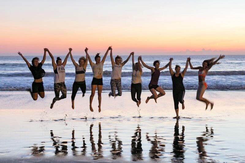 Women at Ocean Sould retreat, jumping for joy on the bali beach at sunset